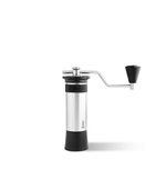 Kinu manual coffee grinder with 47mm Black-Fusion conical burrs, smooth ball-bearing mechanism, and EVA travel case, engineered for speed, precision, and portability.