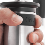 Kinu manual coffee grinder with 47mm Black-Fusion conical burrs, smooth ball-bearing mechanism, and EVA travel case, engineered for speed, precision, and portability.