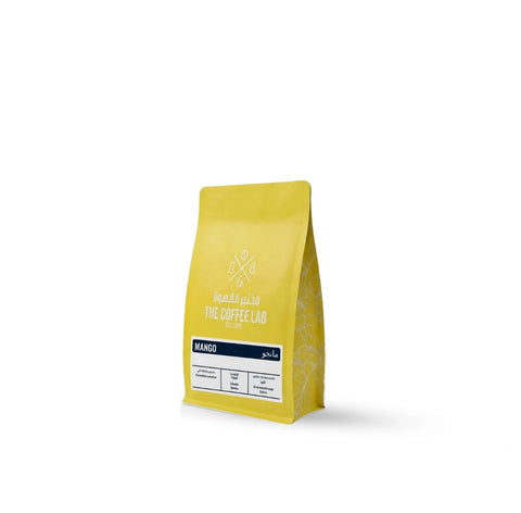The Coffee Lab Mango specialty whole bean coffee from Colombia featuring Caturra Arabica beans with mango co-fermentation process in bright yellow packaging.