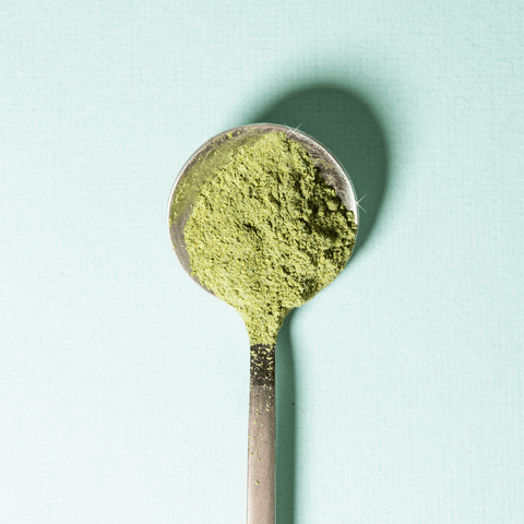A silver spoon filled with vibrant green matcha powder, perfect for making Matcha Lemonade.