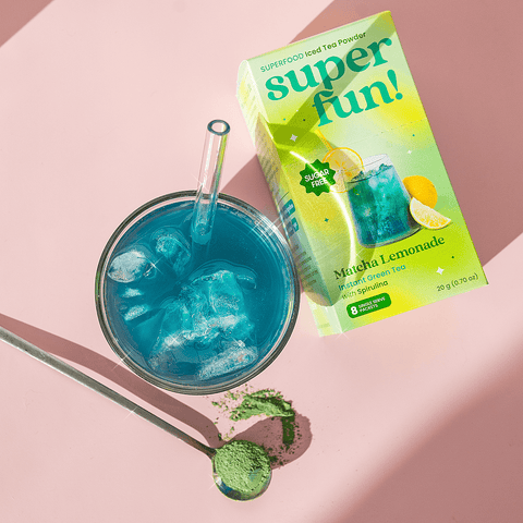 Matcha Lemonade beverage and packaging with blue ice drink on a pink background.