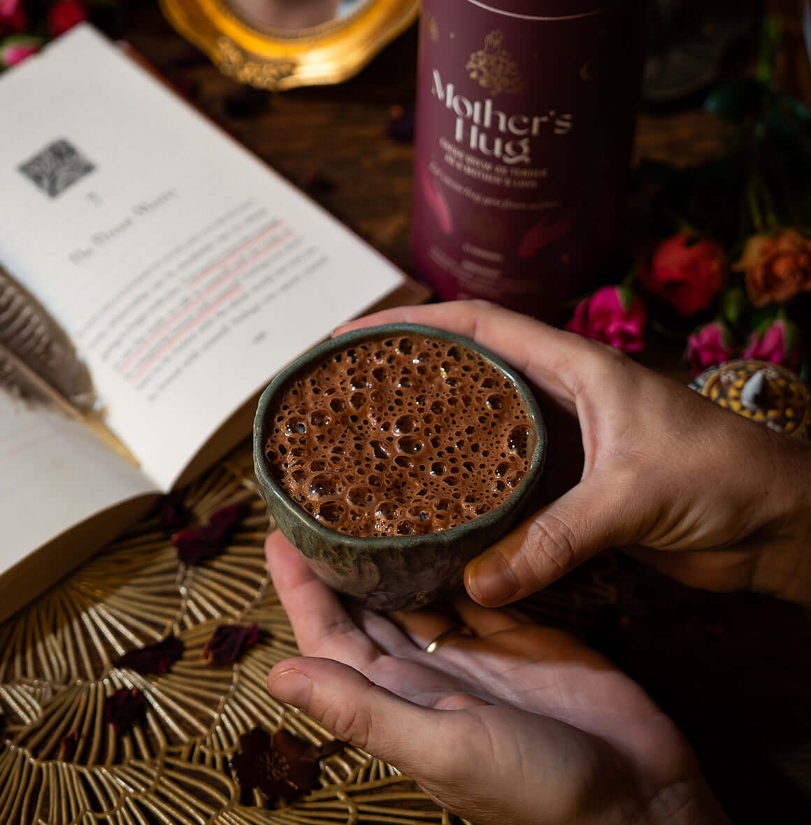 Mother’s Hug cacao brew packaging with a warm maroon design, featuring celestial gold details and spiritual hand illustrations.