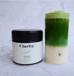 Clarity Koicha matcha green tea powder in a double-walled glass bowl beside a ceremonial matcha tin, smooth and vibrant in color.