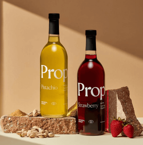 Two bottles of Proper Natural Syrups: Pistachio Syrup and Strawberry, gluten-free and vegan options.
