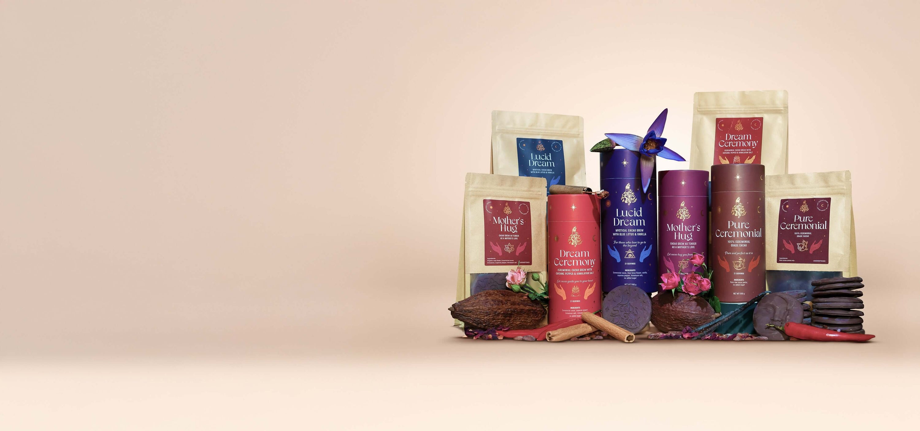 An assortment of Seeds of Power cacao products, including cylindrical and pouch packaging of Lucid Dream, Dream Ceremony, Mother’s Hug, and Pure Ceremonial, surrounded by cacao beans, chocolate pieces, spices, and flowers.
