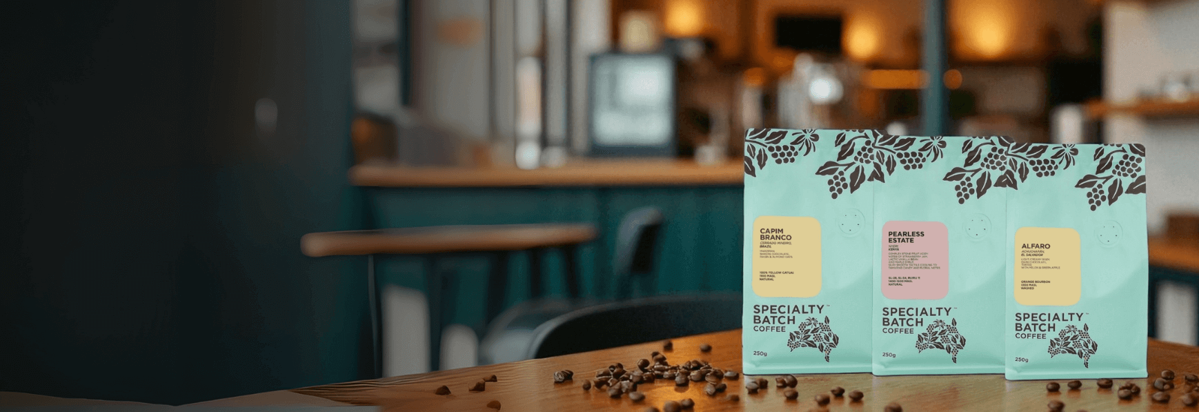 Three coffee bags with labels on a wooden surface in a blurred cafe setting