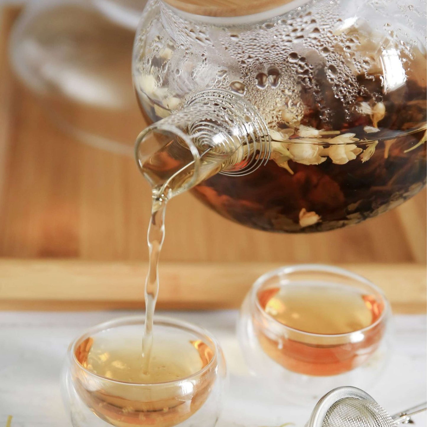 Organic Whole Camomile Blossoms tea pouring into glass cups, showcasing its floral and naturally sweet infusion, perfect for relaxation.