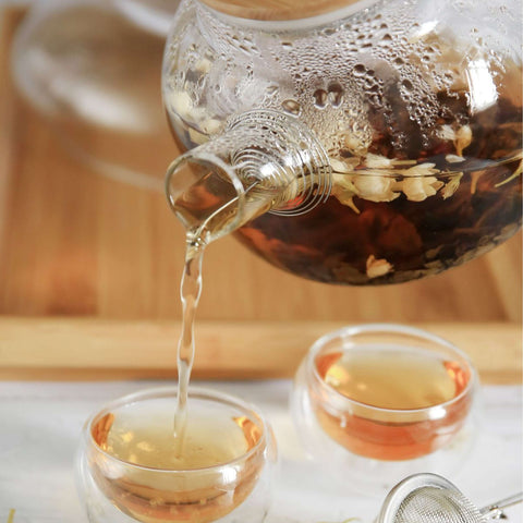 Organic Whole Camomile Blossoms tea pouring into glass cups, showcasing its floral and naturally sweet infusion, perfect for relaxation.