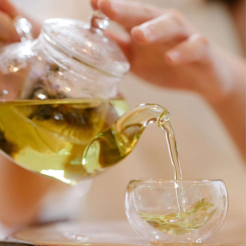 Pouring Organic Earl Grey Harington Estate Tea into a glass cup, showcasing its rich color and inviting aroma.