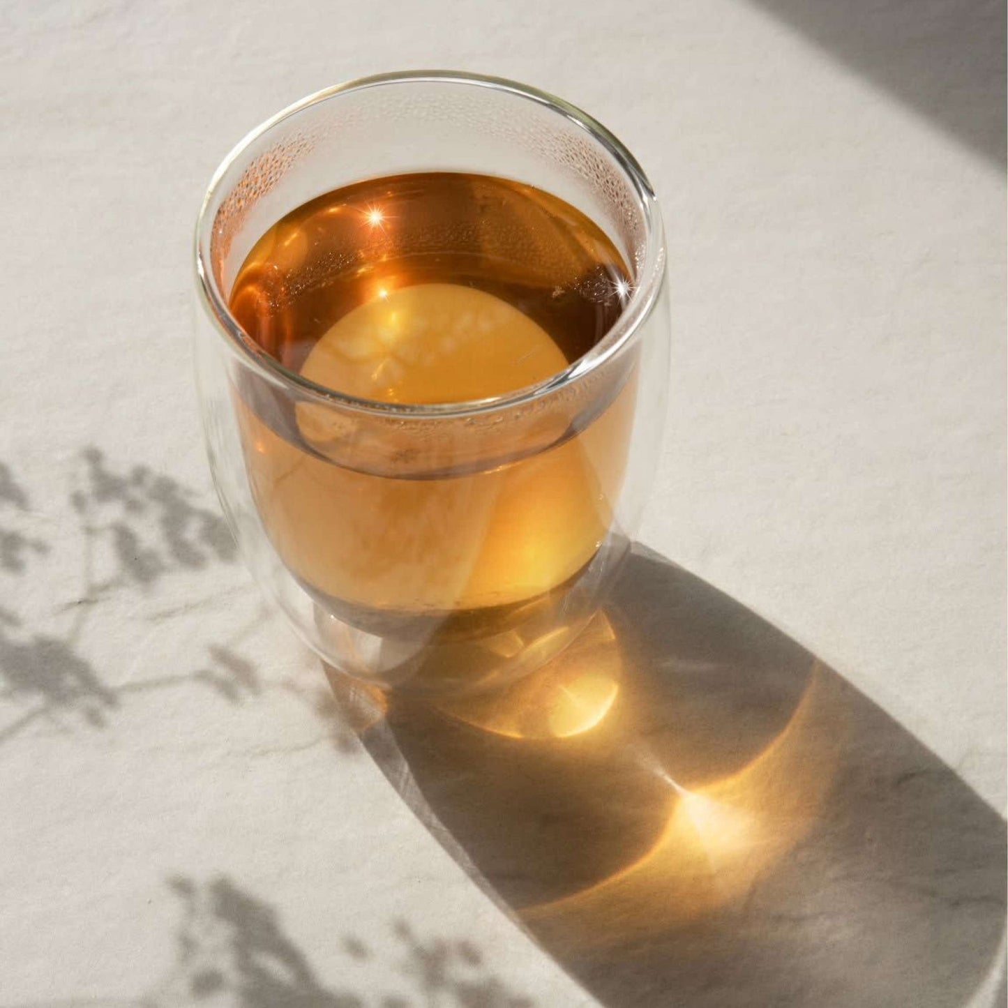 Glass of Blood Orange Tea reflecting light, showcasing its zesty and refreshing appearance perfect for a summer iced tea cocktail.