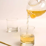 Pouring Organic Green Tea Thotulagalla Estate into a glass, showcasing its light vegetal notes and meadow sweetness.