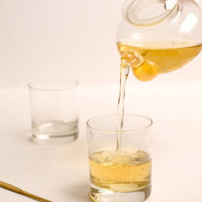 Pouring Organic Green Tea Thotulagalla Estate into a glass, showcasing its light vegetal notes and meadow sweetness.