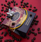 Premium ground specialty coffee box with a butterfly brooch and coffee beans on a red background.