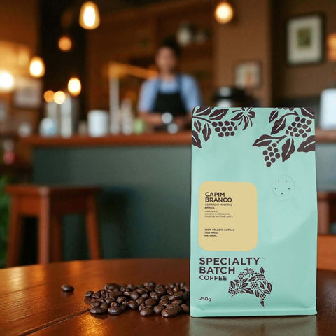 Capim Branco Specialty Batch Coffee package on a table with coffee beans in a bar setting