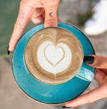 Organic Japanese hojicha with latte art in a blue cup, showcasing the roasted tea's caramel sweetness and versatility.