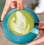 Cup of Japanese organic ceremonial matcha with latte art on a blue saucer, showcasing deep umami and vegetal sweetness.